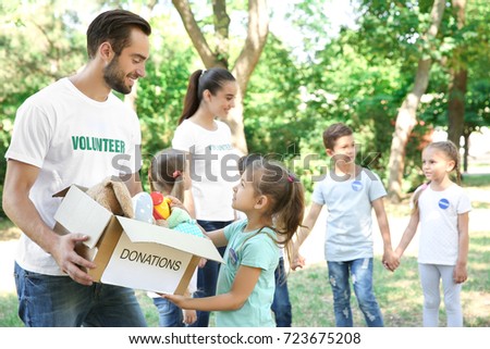 Young volunteers and children with box of donations outdoors Royalty-Free Stock Photo #723675208