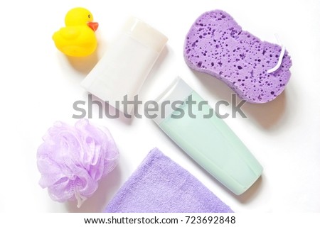Yellow rubber duck, purple sponge puff, shampoo bottle, purple terry towel and sponge puff. Flat lay baby bath products. Organic cosmetics for bathroom. Many items