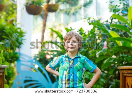 Little blond preschool kid boy discovering flowers and butterflies at botanic garden. Schoolchild interested in biology. Active educational leisure with kids in museum.