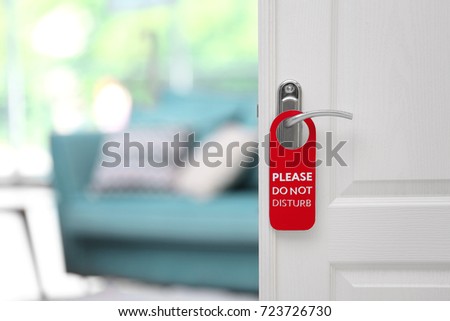 Open door with sign PLEASE DO NOT DISTURB on handle at hotel