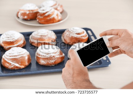 Young blogger taking photo of tasty pastry in kitchen