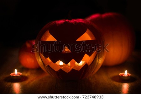 halloween and holidays concept - spooky jack-o-lantern or carved pumpkin lantern burning in darkness
