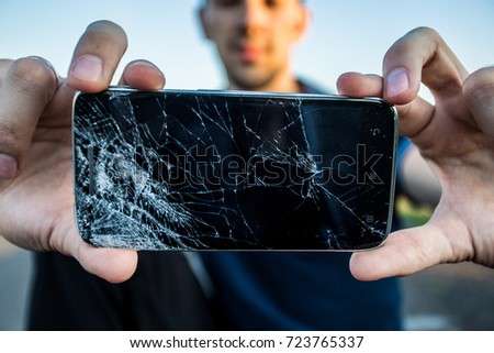 Men's hands hold a smart phone with a cracked screen