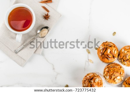 Autumn and winter baked pastries. Healthy pumpkin muffins with traditional fall spices, pumpkin seeds. With tea cup. White marble table, copy space top view