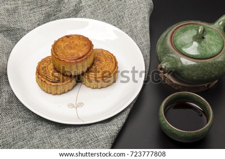 Moon cakes and tea cups and teapots on the black background