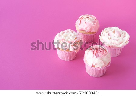 Pink cupcakes with white whipped cream in form of flower on pink background. Picture for a menu or a confectionery catalog.