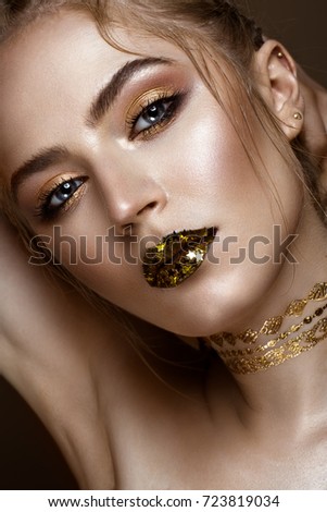 beautiful girl with a golden shiny make-up and stars on her lips. Beauty face. Photo taken in the studio.