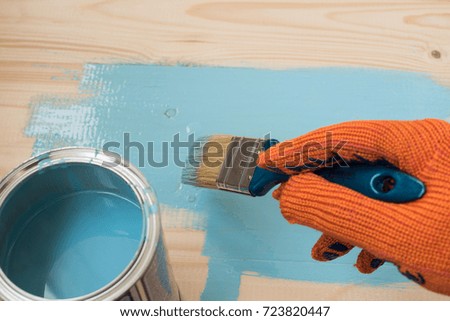 worker paints board blue paint. concept of repair, copy space, space for text. the employee paints the a wooden table

