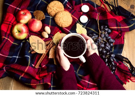 Hand keeping cup of coffee Apple Cookies Cinnamon Grape Wooden background Autumn blanket Autumn lifestyle concept Top view