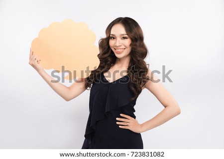 Smiling young woman holding empty speech bubble while standing on white background
