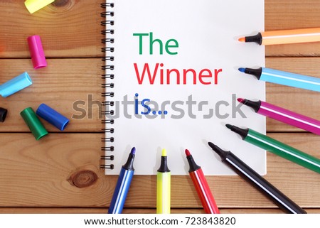 The Winner Is concept with notebook on wooden table