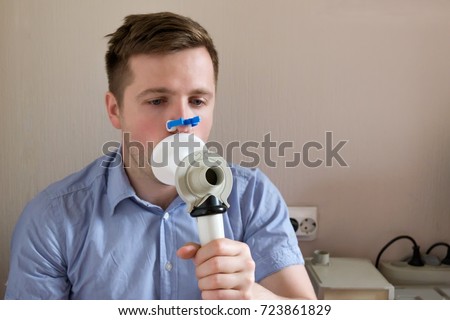 Young man testing breathing function by spirometry. Take care about health. Royalty-Free Stock Photo #723861829