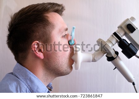 Young man testing breathing function by spirometry. Take care about health. Royalty-Free Stock Photo #723861847