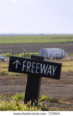 A small sign points the way to the freeway, which can be seen in the distance.