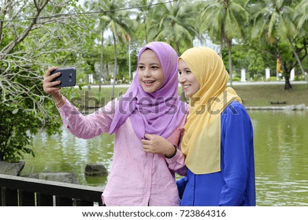 Happy professional muslimah having fun, spend time together and making selfie in the city park