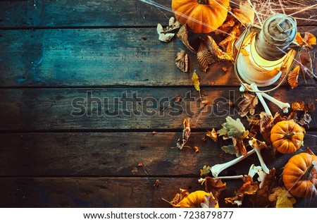 High angle view of halloween pumpkins with bones and vintage lamp under spider web against wooden background