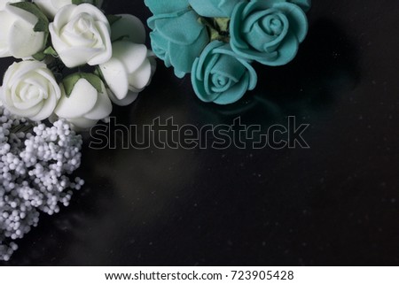 Ornaments for celebrations. A bouquet of artificial flowers from white foam plastic, rose beige and emerald colors. Located in the left corner of the frame.