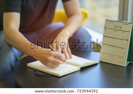 Man writing diary or notebook with calendar 2018 on table. Organize planing business event, schedule to support business organizer and booking timeline for payment reminder. Calendar 2018 concept Royalty-Free Stock Photo #723944392