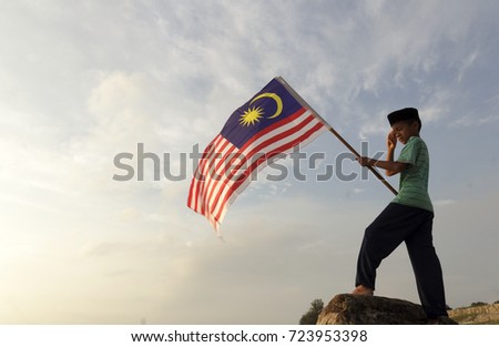 The Concept of Independence Day - a boy holding the Malaysian flag on the shore