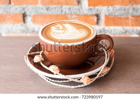 A cup of capuccino latte art coffee and rose on orange brick background.