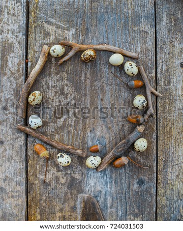 "Wreath" with quail eggs, acorns and dry branches on an old rustic table. Decorative frame for holiday design.