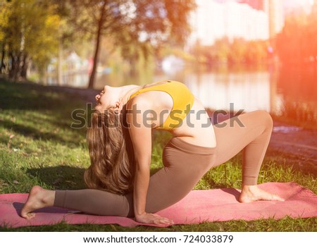 Portrait of young woman in autumn city park. Sport girl doing yoga outside.