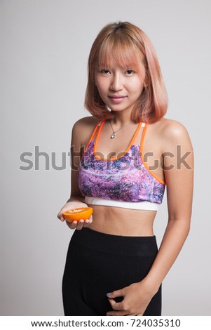 Beautiful Asian healthy girl with orange fruit on gray background