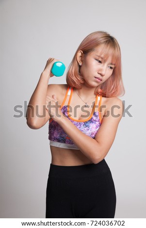 Asian healthy girl got arm pain with dumbbell on gray background