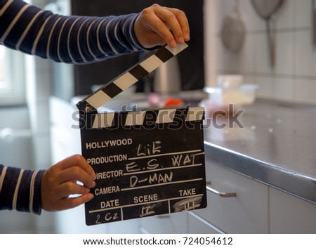Clap board in the kitchen, filming a woman cook