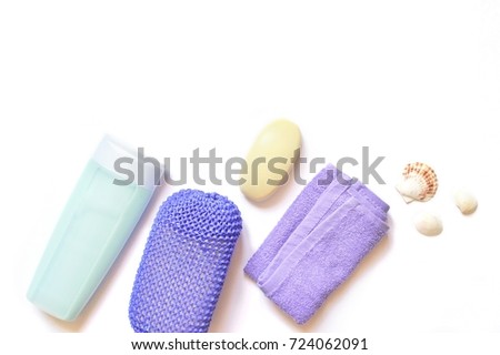 Blue shampoo bottle, purple sponge, terry towel, baby soap and seashells on a white background. Flat lay spa cosmetics, bath products. Flat lay stock photo, top view