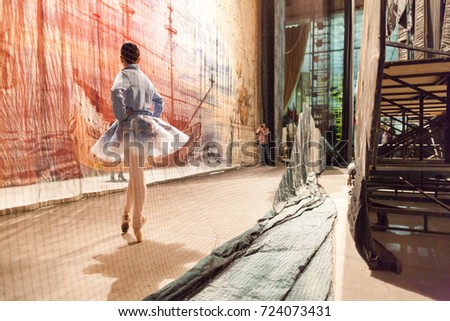 rehearsal, ballet, design concept. surrounded by decoration young beautiful ballerina wearing in light blue tutu and warm cosy sweater stretching before the perfomance Royalty-Free Stock Photo #724073431