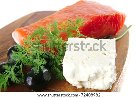 single pink salmon bit on a big wooden dish with white cheese . shallow dof