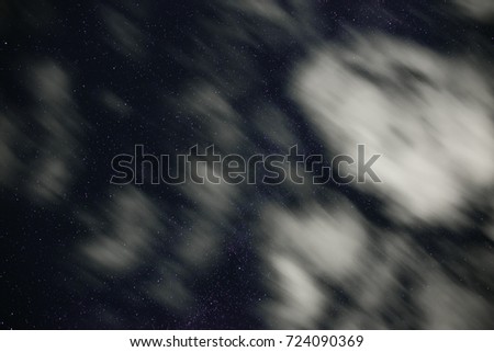 Background of dark-blue night sky with countless twinkle stars and moving white clouds upon on it.