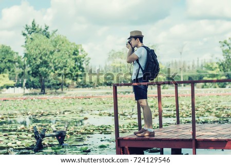 Young man tourists shooting vintage camera and backpack, shooting style, travel style in the park.