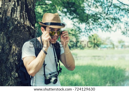Young man tourists shooting vintage camera and backpack, shooting style, travel style in the forest.