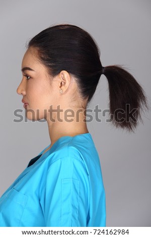 Asian Woman after applying make up black hair style blue shirt. no retouch, fresh face with acne, nice and smooth skin. Studio lighting grey background, rear side back view