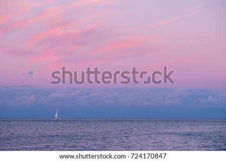 Chicago skyline picture during beautiful and colorful sunset with sailboat on the water of Lake Michigan and pink clouds in the blue sky above