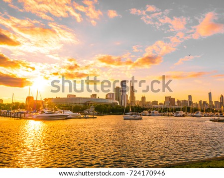 Chicago skyline picture during beautiful and colorful sunset with building silhouettes and boat harbor in the foreground on Northerly Island and pink and orange clouds in blue sky above