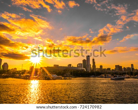 Chicago skyline picture during beautiful and colorful sunset with building silhouettes and boat harbor in the foreground on Northerly Island and pink and orange clouds in blue sky above