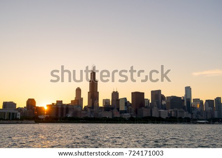 Chicago skyline picture during beautiful sunset with building silhouettes and rippling waves of Lake Michigan water in the foreground