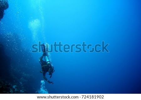 Scuba diver going deep in the ocean taking a selfie. Action and adventure sports background.