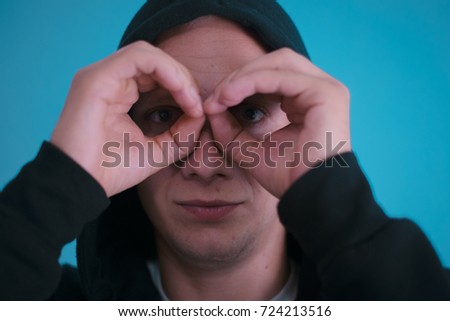 man looking through hands, making binoculars