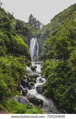 Cascadas de Peguche, a small waterfall in a lush green outdoors in Ecuador, close to the city of Otavalo. Picture taken on a hazy cloudy day.