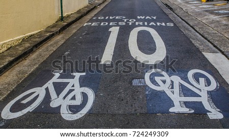 Warning sign for a cyclist to give way to pedestrians and speed limit, not over 10 km per h, it shows painted on the road.