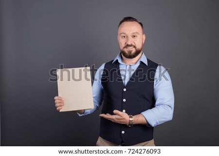 Man Holding Blank Paper on Black Background. Confident businessman in shirt and waistcoat holding a book