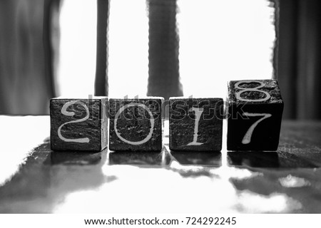 The end of 2017 and the beginning of the 2018. Wooden black cubes with numbers. Happy new year. Black and white picture.