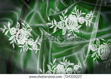 Texture, background, pattern. Lacy white fabric. Flowers made of lace fabric. Green background of silk fabric. greeting card. Wallpaper for your desktop. Screensaver backdrop for designer