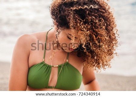 Beautiful woman portrait on the beach with gorgeous curly hair