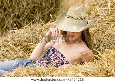 Beauty cowgirl relaxing in the straw in field