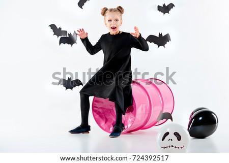 Little girl witch in black dress over magical accessories. Halloween